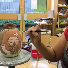 A woman painting some pottery she has created